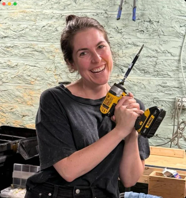 A student smiling while holding a cordless drill