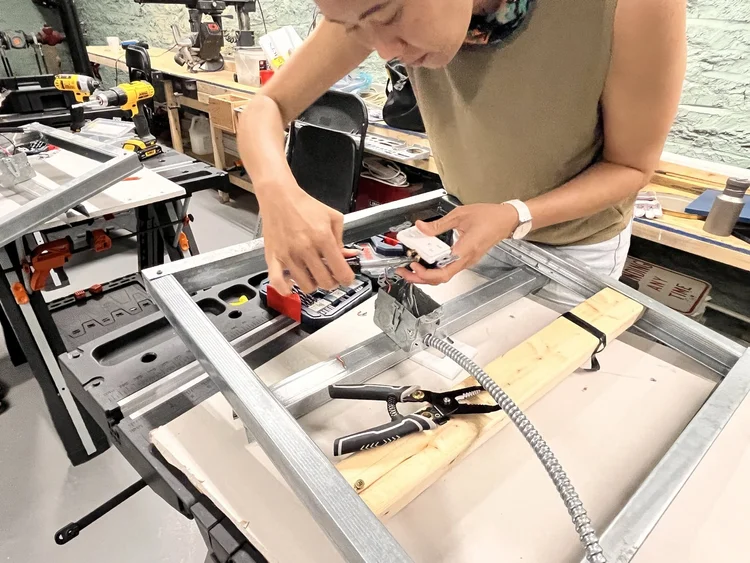 A participant wiring an electrical box at the workbench